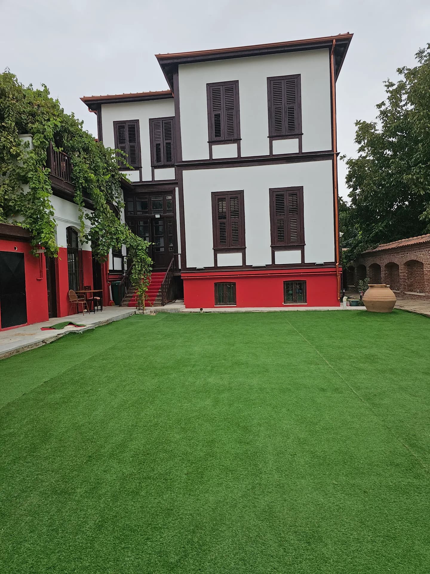 Tarihi konak cephesi, kırmızı sıva ve asma çardak