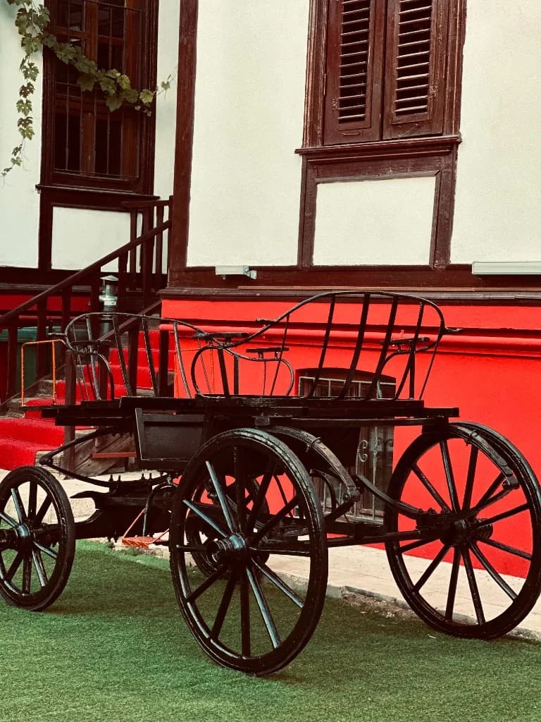 Yeşil çimde vintage fayton, kırmızı konak duvarı